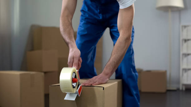 Moving company worker packing cardboard boxes quality delivery services